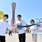 ポスターにちなんだポーズでランナー募集開始をＰＲする神戸マラソン実行委員会事務局の職員＝神戸市中央区波止場町