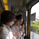 尼崎ＪＲ脱線事故から２１年、事故現場付近を通過する電車内で手を合わせる人たち＝２５日午前９時１６分、尼崎市（代表撮影）