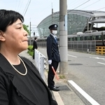 現場周辺で電車を見つめ、唇をかみしめる原口佳代さん。夫浩志さんを事故で失った＝２５日午前、尼崎市久々知西町２（撮影・斎藤雅志）