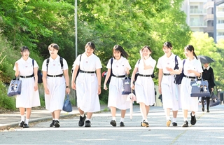 日差しを浴びながら、伝統の白い夏服を着て登校する生徒たち＝１１日午前、神戸市灘区王子町（撮影・斎藤雅志）