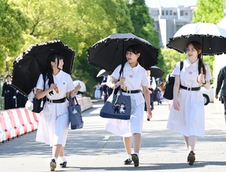 日傘を差し、伝統の白い夏服を着て登校する生徒たち＝１１日午前、神戸市灘区王子町（撮影・斎藤雅志）