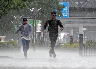 突如降り出した大雨を受けながら、横断歩道を走る人たち＝１３日午後２時１６分、神戸市中央区東川崎町１（撮影・風斗雅博）