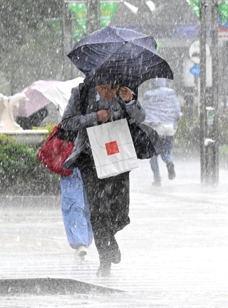 ひょう混じりの激しい雨の中を足早に歩く人たち＝１３日午後、神戸市中央区東川崎町１（撮影・斎藤雅志）