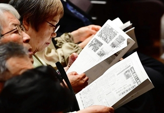 １９７７年当時の新聞や世相を紹介した冊子を眺める式典参加者＝姫路市神屋町
