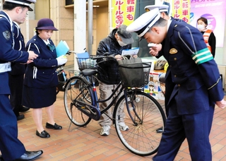 青切符導入に合わせ、自転車利用者に啓発する生田署員ら＝４月１日、神戸市中央区元町通１