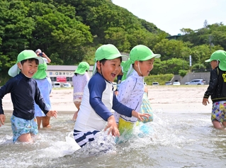 波打ち際で駆け回る園児たち＝25日午前、諸寄・塩谷浜海水浴場