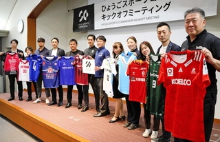 県内各スポーツチームのユニホームを掲げる関係者ら＝神戸市中央区