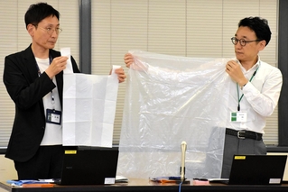 臨時的に使用可能となる１５リットル程度と４５リットルの袋を示す市環境局業務課の担当者ら＝神戸市役所