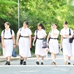 日差しを浴びながら、伝統の白い夏服を着て登校する生徒たち＝１１日午前、神戸市灘区王子町（撮影・斎藤雅志）