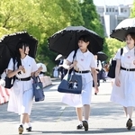 日傘を差し、伝統の白い夏服を着て登校する生徒たち＝１１日午前、神戸市灘区王子町（撮影・斎藤雅志）