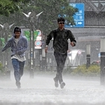 突如降り出した大雨を受けながら、横断歩道を走る人たち＝１３日午後２時１６分、神戸市中央区東川崎町１（撮影・風斗雅博）