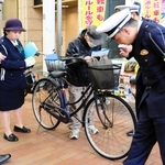 青切符導入に合わせ、自転車利用者に啓発する生田署員ら＝４月１日、神戸市中央区元町通１