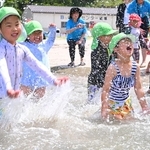 波打ち際で水をかけ合う園児たち＝25日午前、諸寄・塩谷浜海水浴場