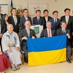 ウクライナ国旗を持つ（右から）黒川治県議、ユーリ・ルトビィノフ駐日ウクライナ大使、岡部芳彦・神戸学院大教授ら＝神戸市中央区港島１（スビトラーナ・ローガンさん提供）