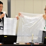臨時的に使用可能となる１５リットル程度と４５リットルの袋を示す市環境局業務課の担当者ら＝神戸市役所