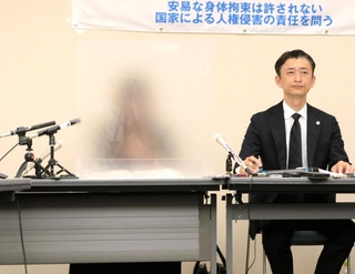 会見でアクリル板越しに少女への思いを語る母親（左）＝１７日午前、神戸市中央区