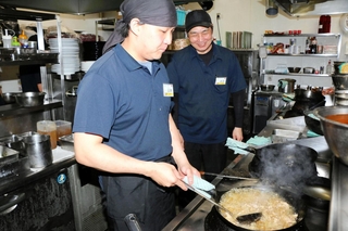 ペルゴの南谷稔宏店長（右）に見守られながら中華鍋を振る清瀬真也さん＝姫路市飾磨区上野田５