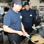 ペルゴの南谷稔宏店長（右）に見守られながら中華鍋を振る清瀬真也さん＝姫路市飾磨区上野田５