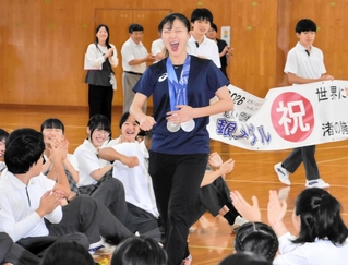 母校の渚中学校を訪問し、生徒らの拍手を受けながら入場する坂本花織さん（中央）＝神戸市中央区、渚中学校