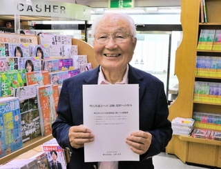 請願採択のプロセスをまとめた冊子を手に思いを語る山根金造さん＝明石市大久保町駅前１