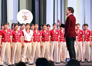 大阪・関西万博会場で「しあわせ運べるように」の合唱指揮をする臼井真さん＝２０２５年５月、大阪市此花区の夢洲