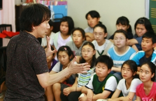 児童らを前に合唱曲「しあわせ運べるように」へ込めた思いを話す臼井真さん＝２０１１年６月、神戸市東灘区住吉東町４、住吉小学校