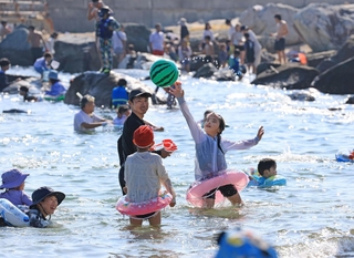 日差しが照りつける中、水遊びを楽しむ親子連れら＝20日午後、神戸市垂水区海岸通（撮影・丸山桃奈）