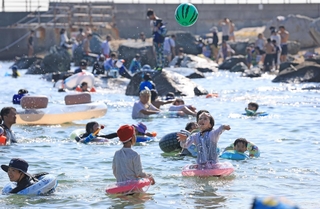 日差しが照りつける中、水遊びを楽しむ人たち＝20日午後、神戸市垂水区海岸通（撮影・丸山桃奈）