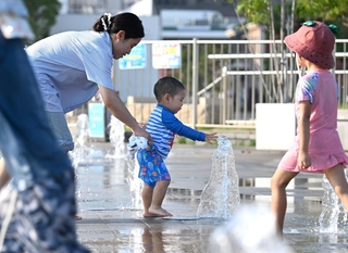 暑さを和らげるため噴水の周りで遊ぶ親子ら＝２２日午後、神戸市中央区波止場町（撮影・風斗雅博）