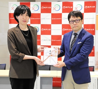 日本ＩＤＤＭネットワークの内野麻里子事業部長（左）から目録を受け取る神戸大の浅利貞毅特命教授＝神戸市中央区楠町７