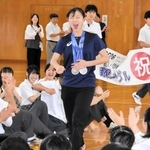 母校の渚中学校を訪問し、生徒らの拍手を受けながら入場する坂本花織さん（中央）＝神戸市中央区、渚中学校