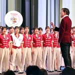 大阪・関西万博会場で「しあわせ運べるように」の合唱指揮をする臼井真さん＝２０２５年５月、大阪市此花区の夢洲