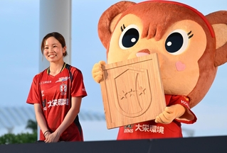 神戸の木材で作ったＩＮＡＣ神戸レオネッサのチームロゴのレリーフと、愛川陽菜選手＝１日午後、神戸市中央区波止場町（撮影・斎藤雅志）