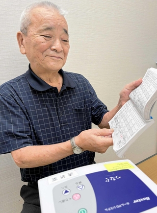 腹膜透析を始めた高上邦雄さん。毎日の透析の記録をノートに付けている＝兵庫県立はりま姫路総合医療センター