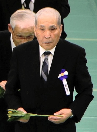 全国戦没者追悼式に参列し、兵庫県の遺族を代表して献花する徳田保幸さん（中央）＝１５日午後、東京都千代田区、日本武道館