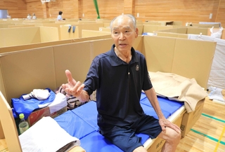 身を寄せる避難所で段ボールベッドに腰かける松田幸四郎さん＝１９日、熊本県宇城市小川町江頭、小川防災拠点センター（撮影・吉田敦史）