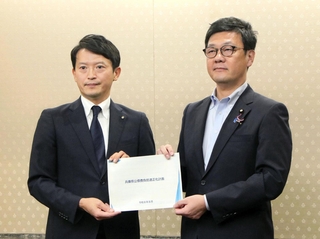 総務省の梶原大介政務官（右）に「公債費負担適正化計画」を手渡す兵庫県の斎藤元彦知事＝東京都千代田区霞が関