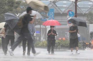 たたきつけるような激しい雨が降る中を歩く人たち＝８日午前、神戸市中央区東川崎町１（撮影・鈴木雅之）