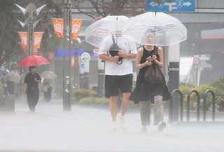 たたきつけるような激しい雨が降る中を歩く人たち＝８日午前、神戸市中央区東川崎町１（撮影・鈴木雅之）