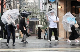 強い雨風の中を歩く人たち＝９日午前９時５９分、神戸市中央区、ＪＲ元町駅前（撮影・鈴木雅之）