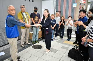 社会福祉法人「きらくえん」の野村友子事務局長（中央）から支援金を託される高橋守雄さん（左端）＝神戸市中央区小野柄通５