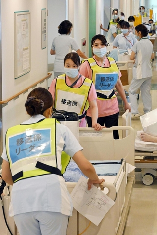 慎重に患者を移送する病院の関係者ら＝２２日午前、西宮市武庫川町、兵庫医科大病院（撮影・大田将之）