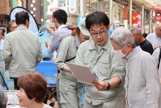 神戸市の水道ＰＲイベントで悪質業者への注意を呼びかける市水道局職員＝６月４日、同市中央区の元町３丁目商店街