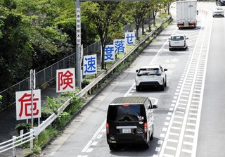 乗用車やトラックが行き交う県道灘三田線。山麓の区間には減速やエンジンブレーキの利用を呼びかける看板が目立つ＝神戸市灘区