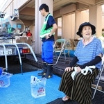 避難所で給水を受ける浜田えい子さん（右）＝熊本県八代市鏡町内田、鏡コミュニティセンター（撮影・吉田敦史）