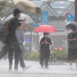 たたきつけるような激しい雨が降る中を歩く人たち＝８日午前、神戸市中央区東川崎町１（撮影・鈴木雅之）