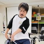 さおの先にパンツのベルト通しをひっかけて足を入れる「メイクユースマイル神戸」のモデル・板垣宏明副理事長＝神戸市西区