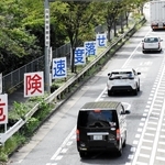 乗用車やトラックが行き交う県道灘三田線。山麓の区間には減速やエンジンブレーキの利用を呼びかける看板が目立つ＝神戸市灘区