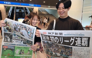 阪神タイガース初のリーグ連覇を伝える神戸新聞の号外を受け取る人たち＝４日午前、神戸市中央区東川崎町１（撮影・鈴木雅之）