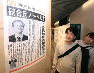 ノーベル化学賞受賞を伝える号外を見る人たち＝７日夜、デュオ神戸（撮影・丸山桃奈）